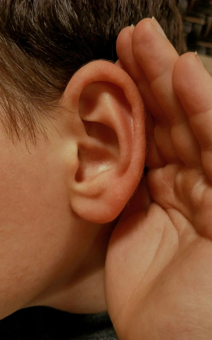 A person cupping their ear to listen closely